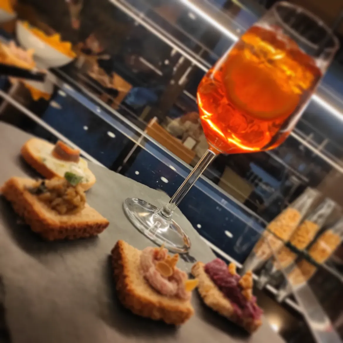 Spritz arancione con cicchetti e tartine su tagliere al banco del Bar Europa